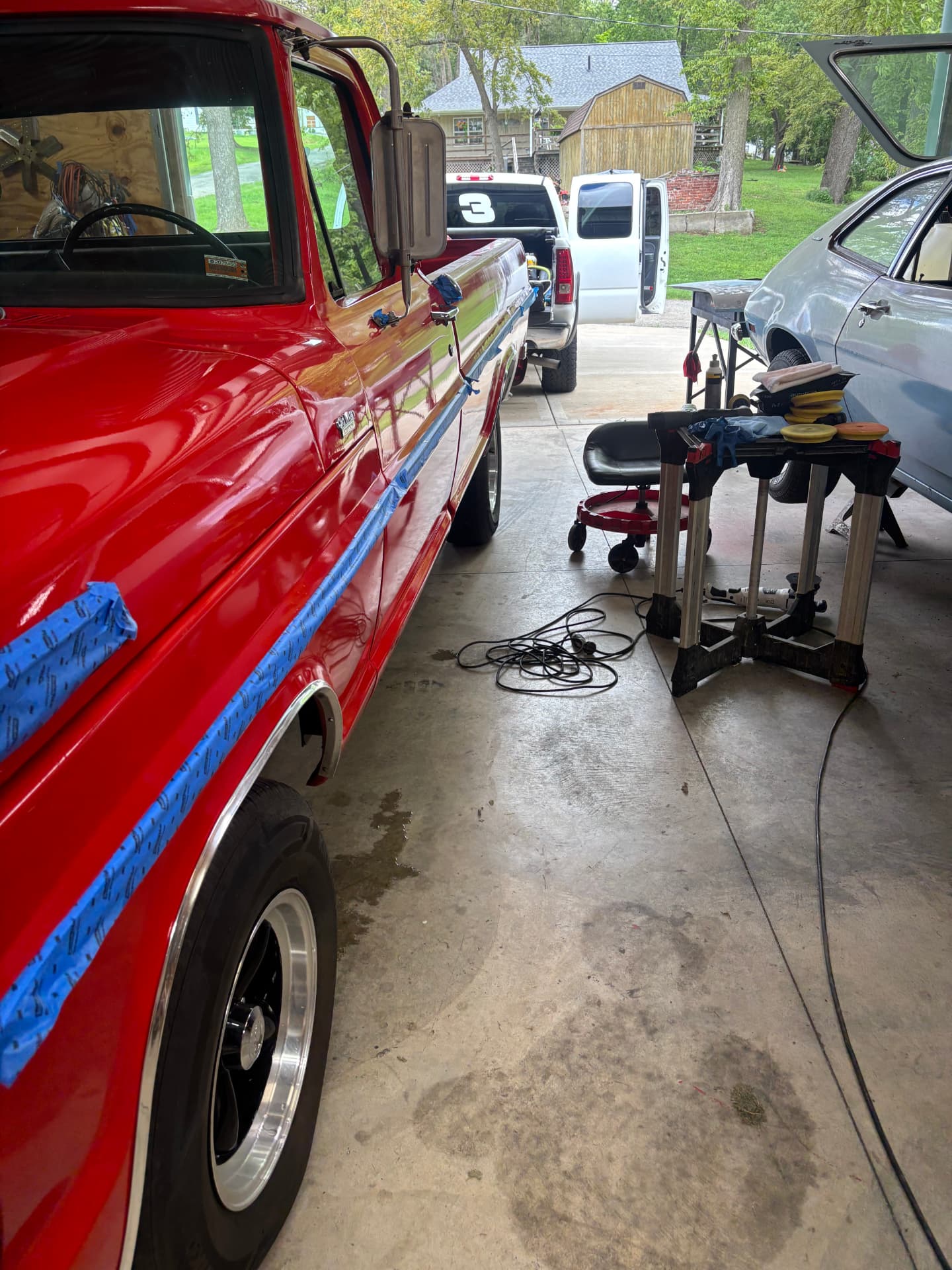 Red classic Ford pickup taped off mid paint correction in the shop